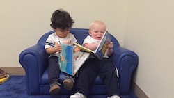 two toddlers reading books