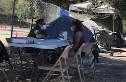 two people in homeless encampment at table